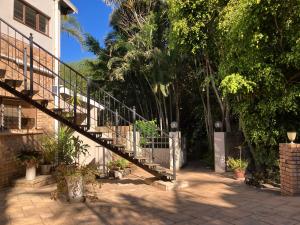 a staircase leading up to a house with trees at Cycasia Lodge in Umzumbe