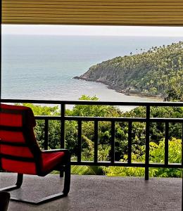 Una silla roja sentada en un balcón mirando el océano. en Dream View Boutique Apartments - Sea View - Near Haad Yao, Secret Beach & Mae Haad, Koh Phangan, en Ko Pha Ngan