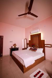 a bedroom with a bed with a ceiling fan at Sreedevi Gardens in Irikkūr