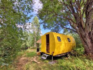 a yellow trailer sitting in the woods next to a tree at Tiny House The Barack in Gunsjögården