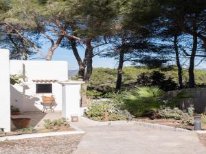 een tuin met een wit huis met bomen op de achtergrond bij Belvilla by Oyo Villa in San Jose de sa Talaia