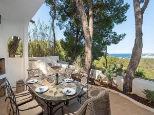 een tafel en stoelen op een patio met uitzicht op de oceaan bij Belvilla by Oyo Villa in San Jose de sa Talaia