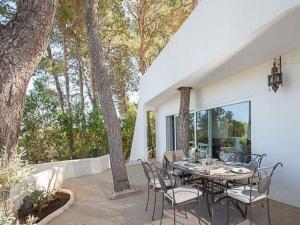 een tafel en stoelen op een patio met bomen bij Belvilla by Oyo Villa in San Jose de sa Talaia