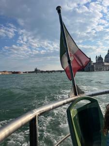 a boat with a flag on the water at Ampia Casa a due passi dalla Biennale in Venice +3 photos