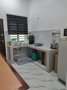 a kitchen with a desk with a sink and a window at Seri Desa Homestay in Kuala Terengganu +2 photos