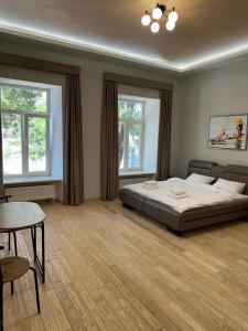 a bedroom with a bed and a table and two windows at Отель Преображенский in Odesa