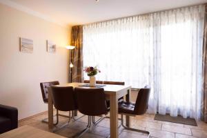 a dining room table with chairs and a vase of flowers on it at MEI27a Ferienwohnung Ostseetraum in Niendorf