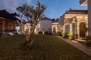 una casa con un árbol en el patio en Villa Sakura III Seminyak, en Seminyak