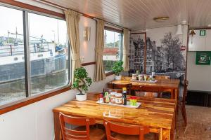 a restaurant with wooden tables and chairs and windows at Neptune Boatique Hotel Amsterdam in Amsterdam +23 photos