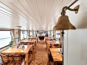 a restaurant with wooden tables and chairs and a bell at Neptune Boatique Hotel Amsterdam in Amsterdam