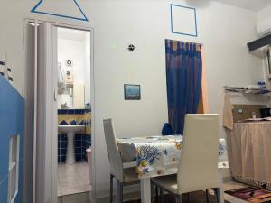 a dining room with a table and two white chairs at La Stanza del Mare in Calasetta