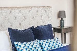 Una cama con almohadas azules y una mesa con lámpara. en Ascot Racecourse Apartment - Free Parking, en Ascot