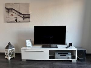 a white entertainment center with a flat screen tv on it at FeWo Büdingen - Atelier in Büdingen