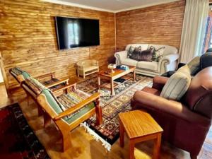 a living room filled with furniture and a flat screen tv at Fireside Cabin in Underberg