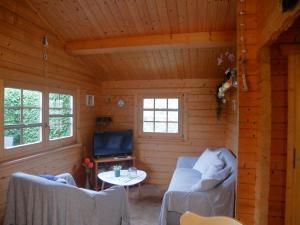 Una habitación con dos sofás y un televisor en una cabaña. en Bungalow Brandl, en Zinnowitz