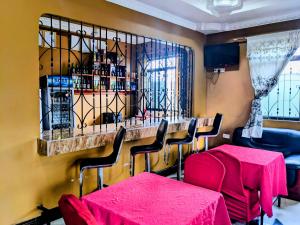 a restaurant with a bar with red tables and chairs at Mauya Executive Lodge in Dar es Salaam +28 photos