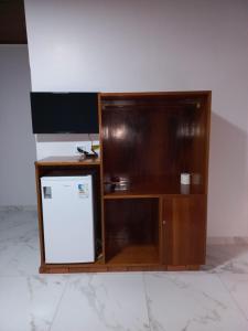 un armario de madera con nevera en una habitación en Hotel Maringá, en Juara