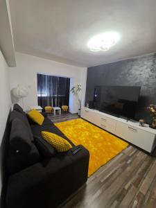 a living room with a black couch and a yellow rug at Panoramic Residence in Blaj
