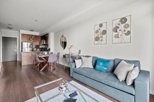 een woonkamer met een blauwe bank en een tafel bij Modern 1Bd & Den Condo with Balcony Lillian St in Toronto