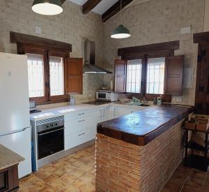 a large kitchen with white cabinets and a brick wall at Casa Rural Mar de Encinas in Cabañas del Castillo
