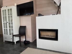 a room with a fireplace and a chair and a television at Villa Hile - 8 hengen mökki, rauhallinen sijainti Himoksen ytimessä in Jämsä