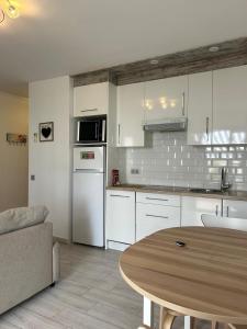a kitchen with white cabinets and a wooden table at Valleverde Apartment in Mijas Costa +37 photos