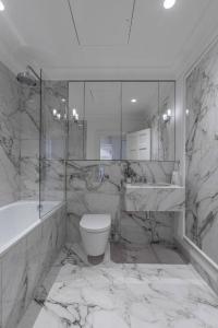 a marble bathroom with a tub and a toilet and a sink at Super Lux 3 Bed Apartment by Mayfair in London