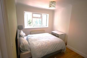 a small bedroom with a bed and a window at 3 Bed Family House and Garden in Hanworth +3 photos