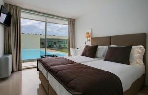 a bedroom with a large bed with a view of a pool at Bom Sucesso Resort in Vau +225 photos