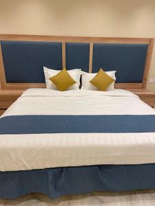 a large bed with a blue head board and pillows at Dani Serviced Apartments in Buqayq +3 photos