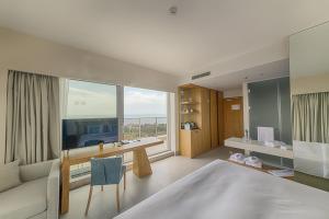Schlafzimmer mit einem Bett, einem Schreibtisch und einem großen Fenster in der Unterkunft Poseidon Beach Resort - a NEW 5-Star Experience - PREMIUM ALL INCLUSIVE, FREE Beach Access, EV station in Goldstrand