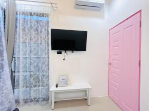 Cette chambre dispose d'une télévision, d'une porte et d'une table. dans l'établissement Hatyai city habibi home 1, à Sathani Hat Yai
