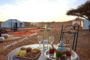 a table with a tray of food and wine glasses at Sahary Tafilalt Luxury Camp in Merzouga