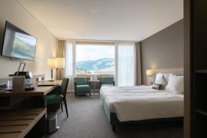 a hotel room with a bed and a desk and a window at Belvédère Strandhotel in Spiez +70 photos