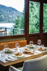 a table with plates of food and wine glasses at Auria Angostura in Villa La Angostura