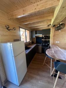 a kitchen with a white refrigerator and a table at Châlet au pied du Puy Mary in Le Claux
