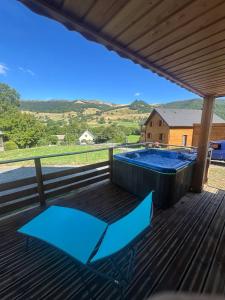 a deck with a blue chair and a hot tub at Châlet au pied du Puy Mary in Le Claux
