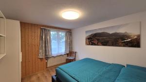 a bedroom with a blue bed and a window at Completely refurbished comfortable apartment in Goldswil