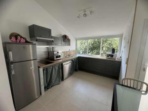 una cucina con frigorifero in acciaio inossidabile e finestra di Villa septembre logement VANILLE a Lamalou-les-Bains