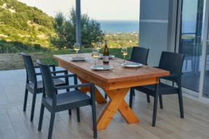 a wooden table with chairs and wine glasses on it at Gold Sun Villa in Ratzaklíon