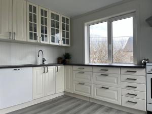 a white kitchen with white cabinets and a window at Sula in Frøya