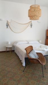 ein Schlafzimmer mit einem Bett und einem Rattanstuhl in der Unterkunft Domus Maregi in Marina di Ragusa