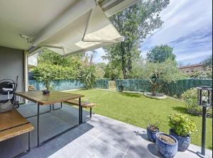 マンドリュー・ラ・ナプールにあるRésidence Ile O Vertの木製テーブルと庭園付きのパティオ