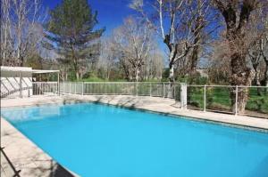 マンドリュー・ラ・ナプールにあるRésidence Ile O Vertの青い塀と木々のあるプール