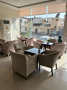 a restaurant with tables and chairs and a large window at Adeem Serviced Apartments in Buqayq