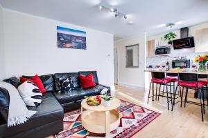 a living room with a black leather couch and a table at Sleeps4-FreeParking-Pets-Wifi-Tottenham Stadium in London