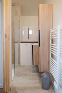 a small kitchen with a glass door and a trash can at Joli studio avec balcon - 2 personnes in Les Sables-dʼOlonne