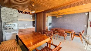 a kitchen and dining room with wooden tables and chairs at Versa - AP TOP na Ponta Verde - 3Q Alto Padrão Climatizado in Maceió