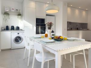 a white kitchen with a white table and chairs at Diana's House - Nazaré in Nazaré