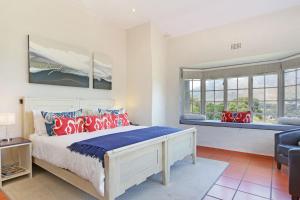 a bedroom with a bed and a chair and windows at Suite SolVista in Cape Town